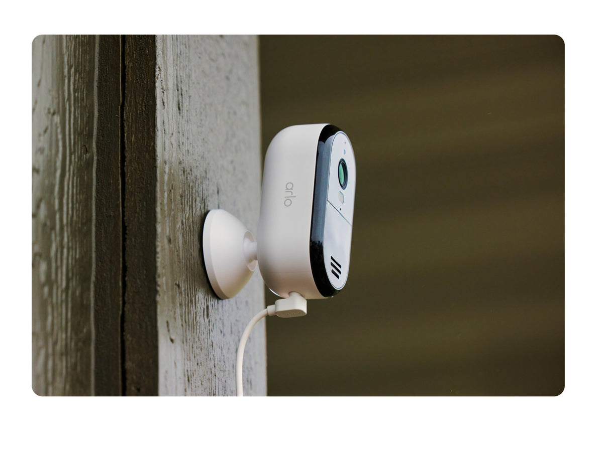 Arlo Essential Plug-In Security Camera attached to a wooden post.