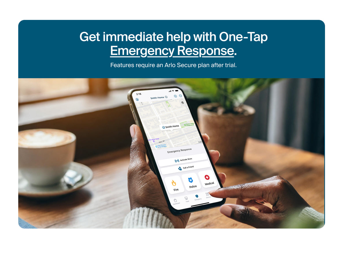 Person using a smartphone with emergency response app on a table with a cup of coffee and plant.