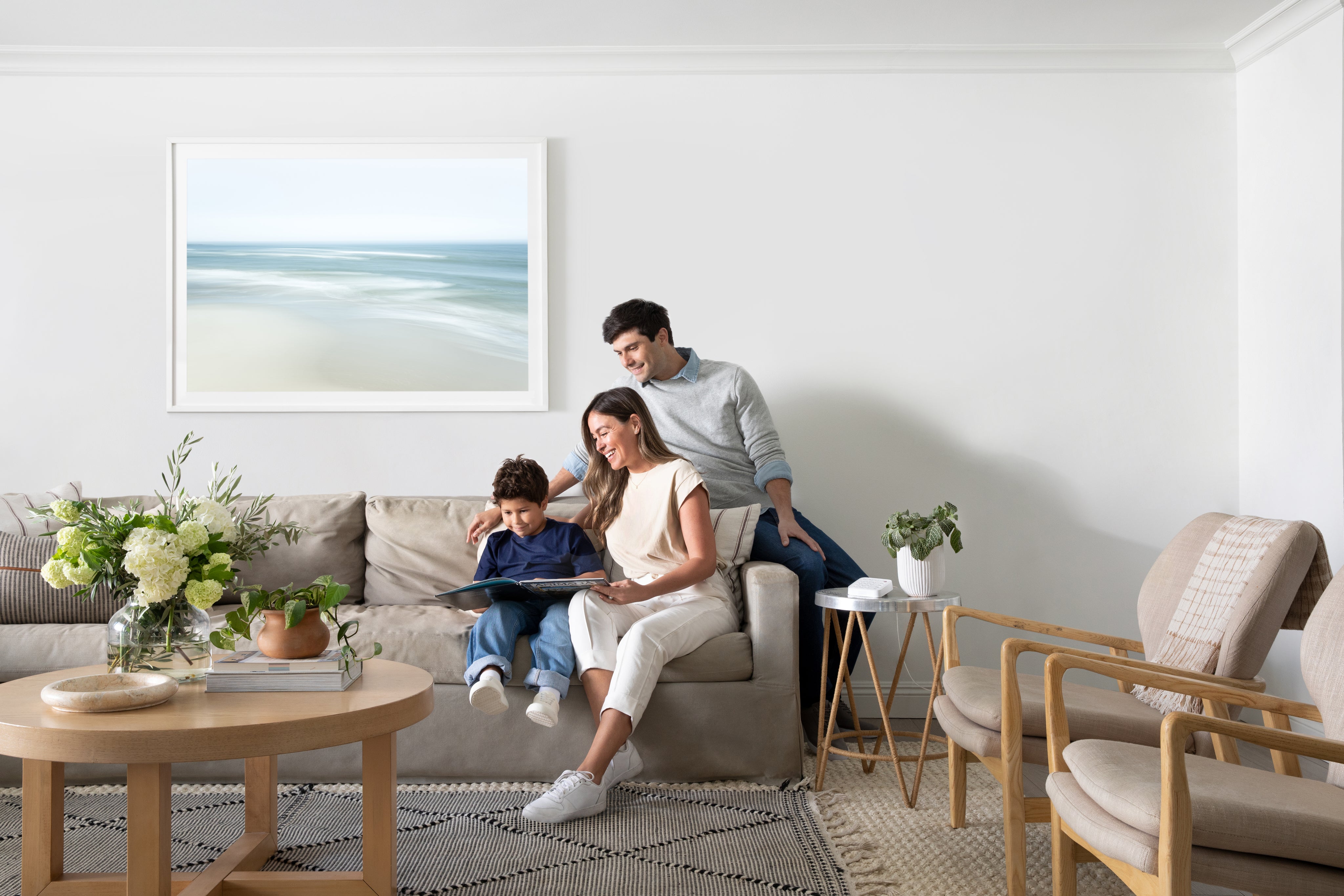 A family sitting on a couch with the Arlo Security System laying on a table top